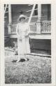 Photo of 1 woman in front of a house.