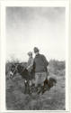 Photo of 1 man in uniform and a boy on a mule.