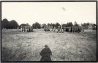 Photo of Men in a Field with Bldg in background