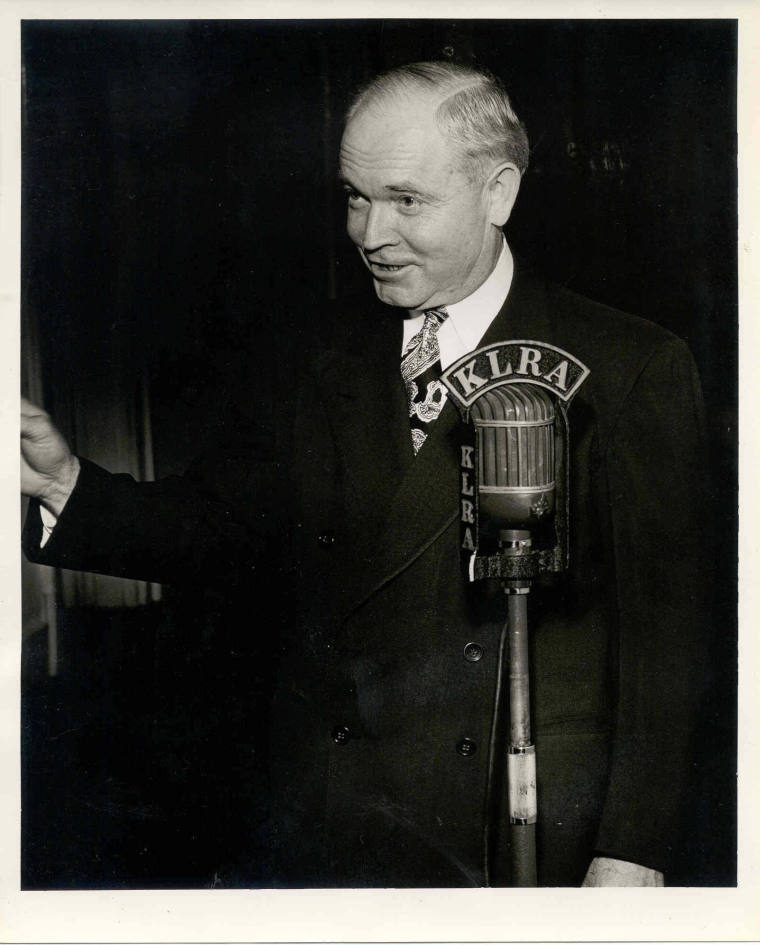 Laney in a suit at a KLRE station microphone.
