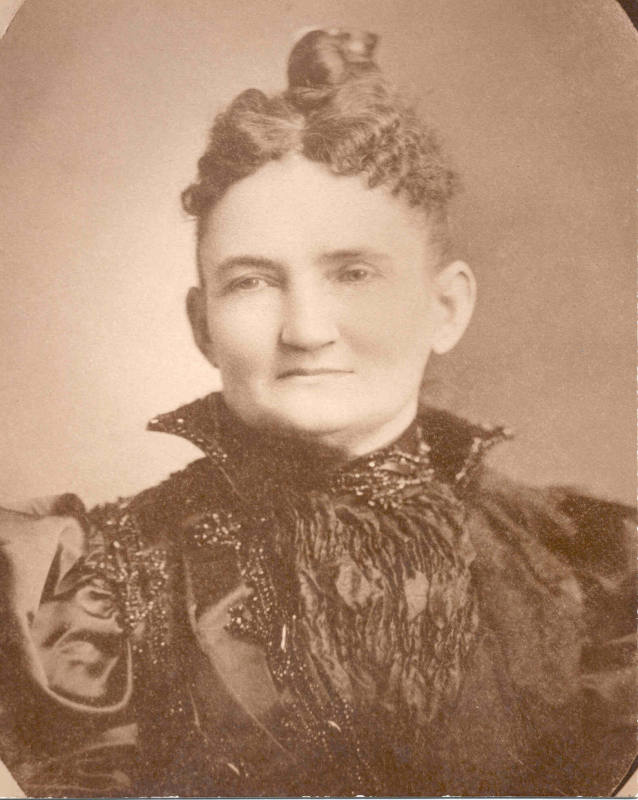 Mrs. Jones wearing a period black taffeta high collar dress.